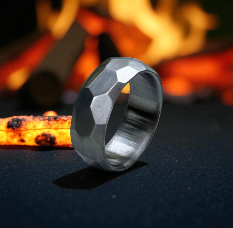 A ring illuminated against a black background, with flames flickering around it, creating a dramatic effect.