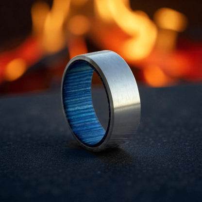Close-up of titanium ring featuring blue wooden inner lining on dark stone background
