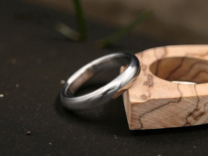 Brushed titanium dome ring resting on wooden accent piece