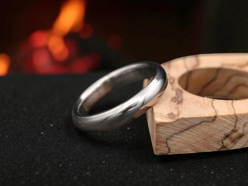 Close-up of polished titanium ring with matte dome surface on dark background