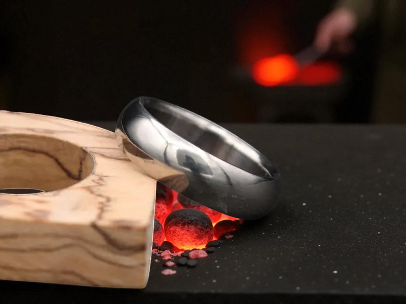 Close-up of titanium dome ring with matte finish and warm firelight reflection