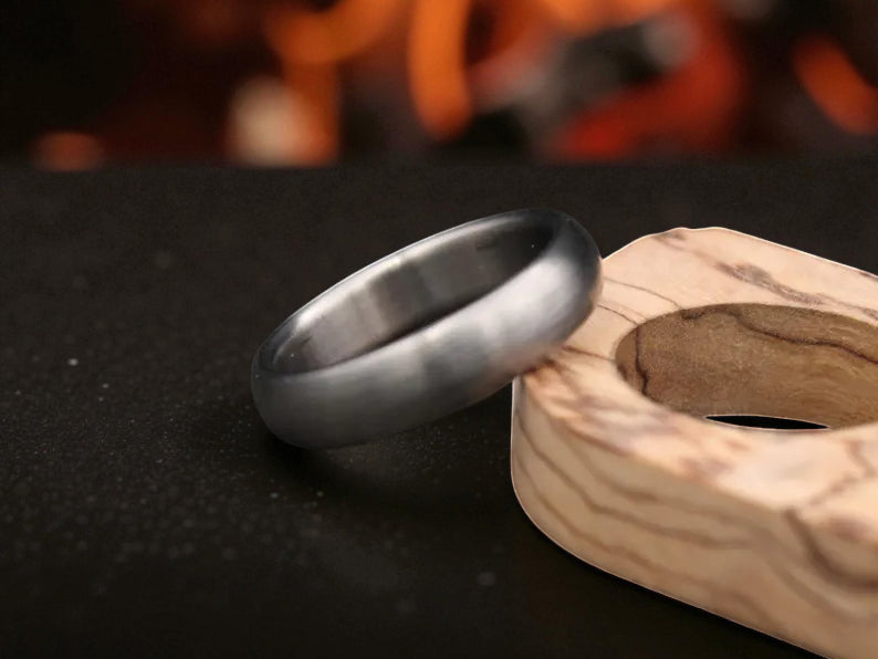 Matte finish titanium dome ring close-up with firelight reflection