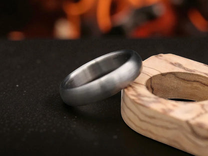 Matte finish titanium dome ring close-up with firelight reflection