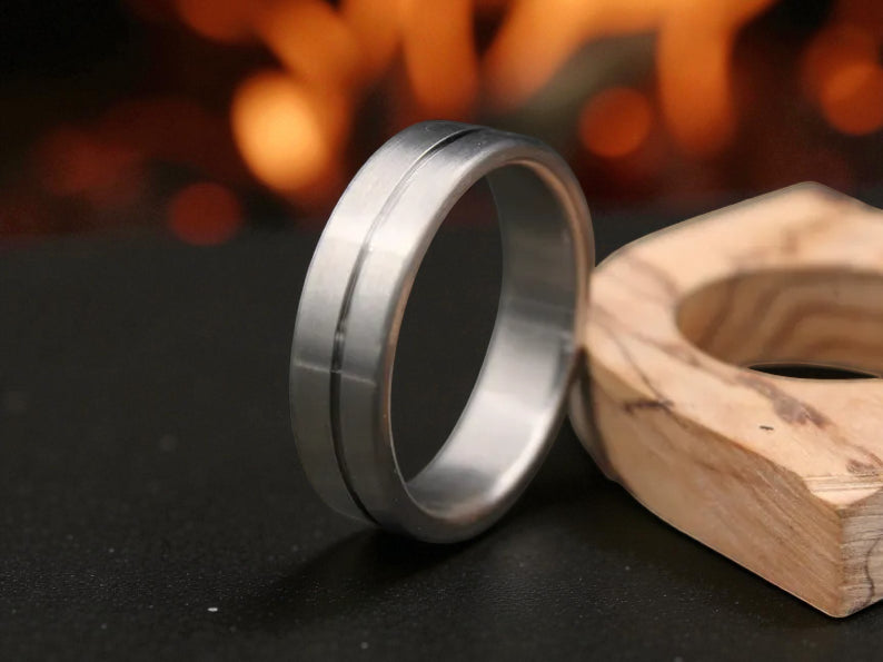 Close-up of titanium ring with brushed finish and subtle center groove on dark surface