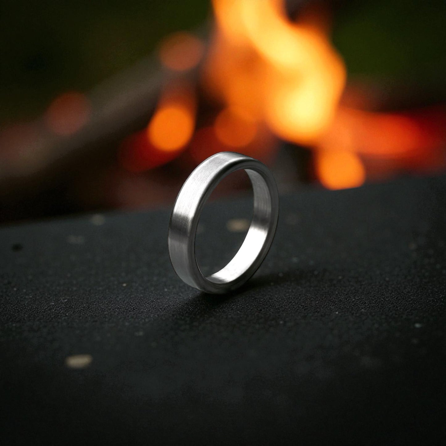 Close-up of matte titanium flat ring with brushed surface resting on dark textured surface