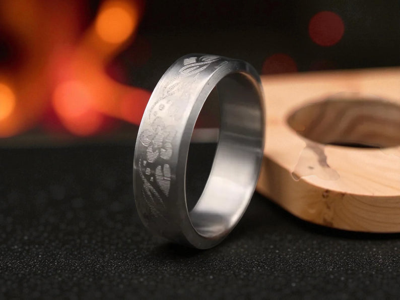 Close-up of engraved titanium band showing detailed floral pattern and matte brushed texture