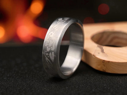 Close-up of engraved titanium band showing detailed floral pattern and matte brushed texture