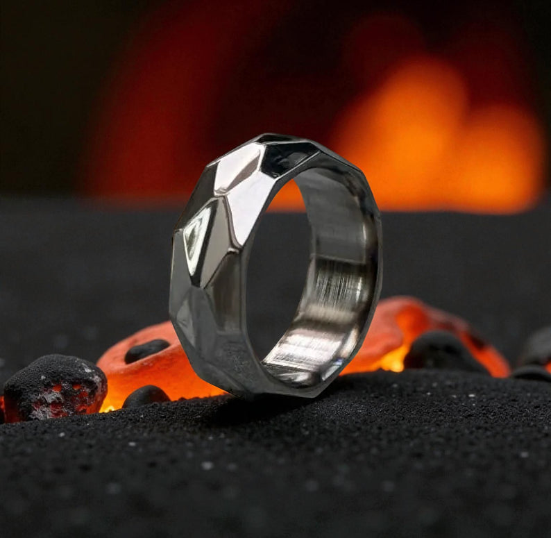Close-up of faceted titanium ring with reflective geometric surfaces and mirror shine