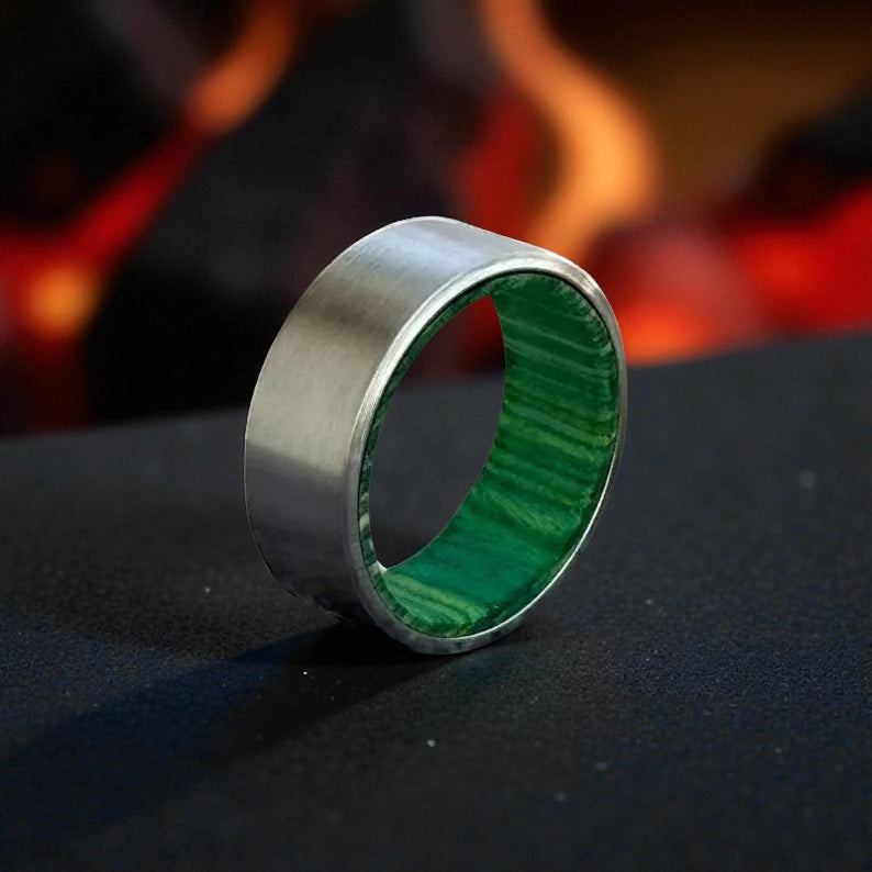 Close-up of titanium ring showing brushed metal surface and vibrant green inner whiskey barrel wood texture