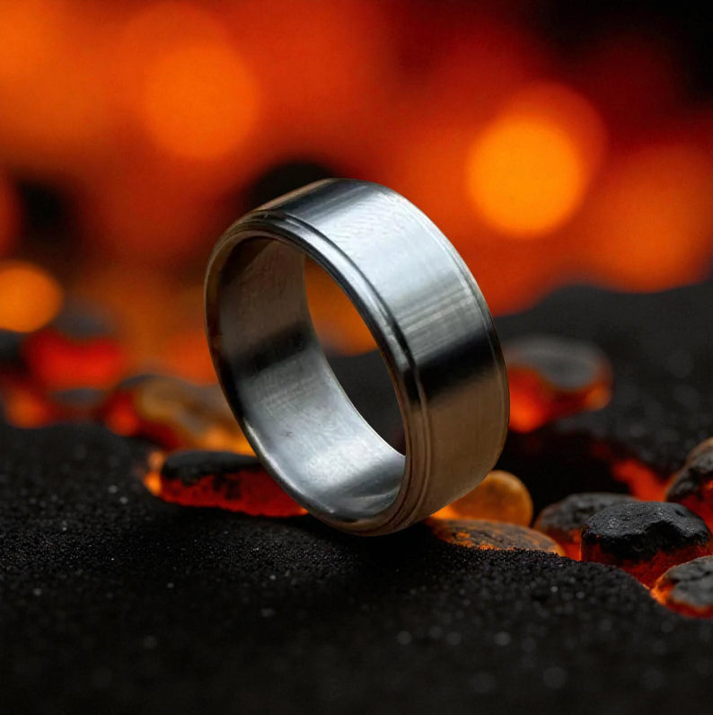 A close-up of a wedding ring placed on a fire pit, with glowing coals and flames creating a warm ambiance.