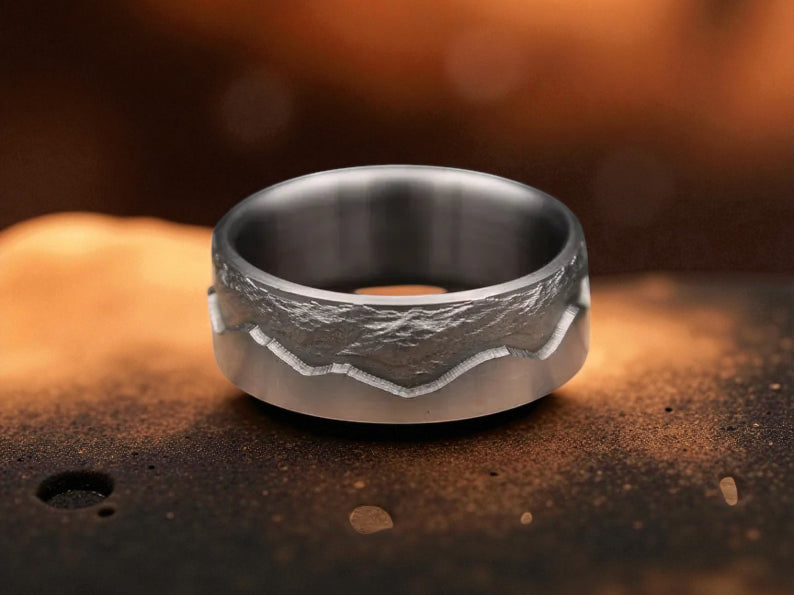 Close-up of titanium mountain ring showcasing textured peak engraving and brushed finish