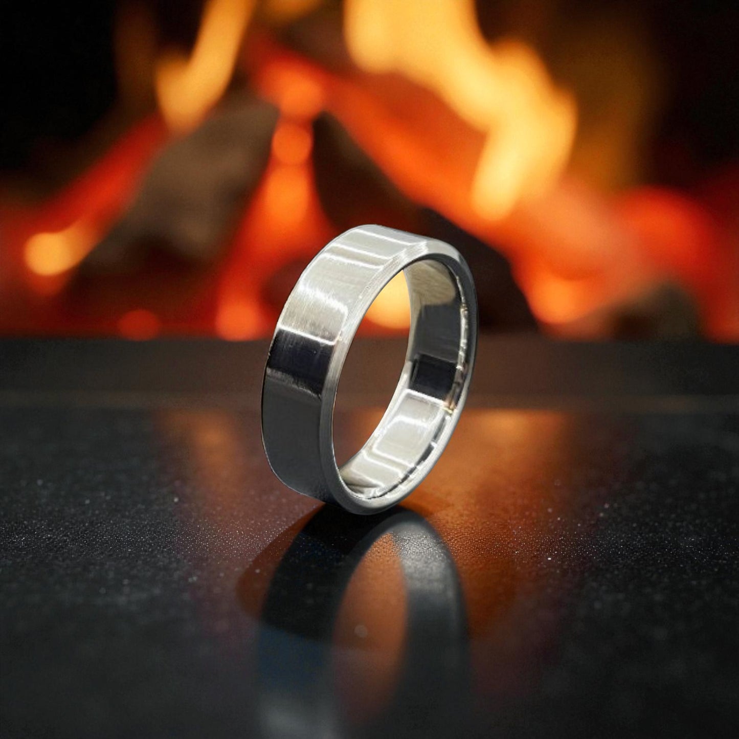 A polished titanium wedding ring rests on a table, illuminated by the warm glow of a nearby fire.