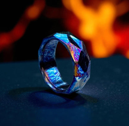 Faceted blue titanium diamond-cut ring on dark surface