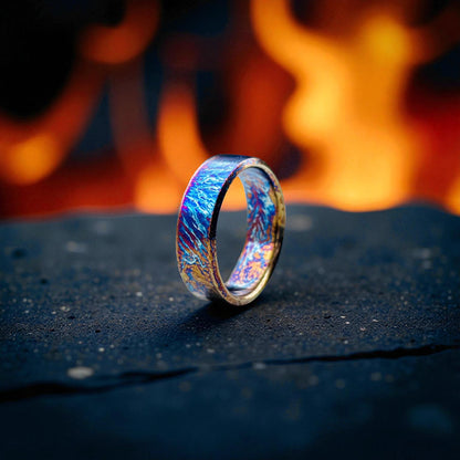 Titanium ring with blue and gold lightning pattern on dark stone surface