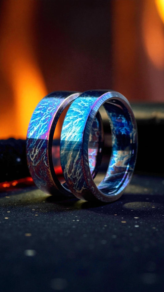 Two titanium rings featuring vibrant blue and purple flames, symbolizing a bold and edgy style.
