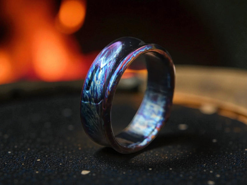 Close-up of polished titanium curved ring with electric tones and soft lighting