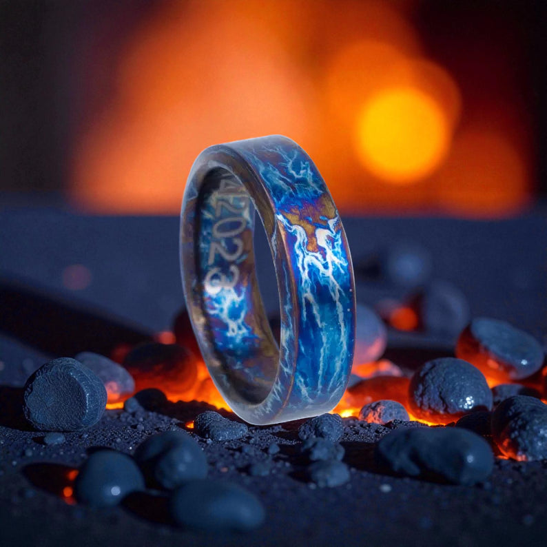 Polished flat-edge titanium ring glowing with blue and gold lightning design