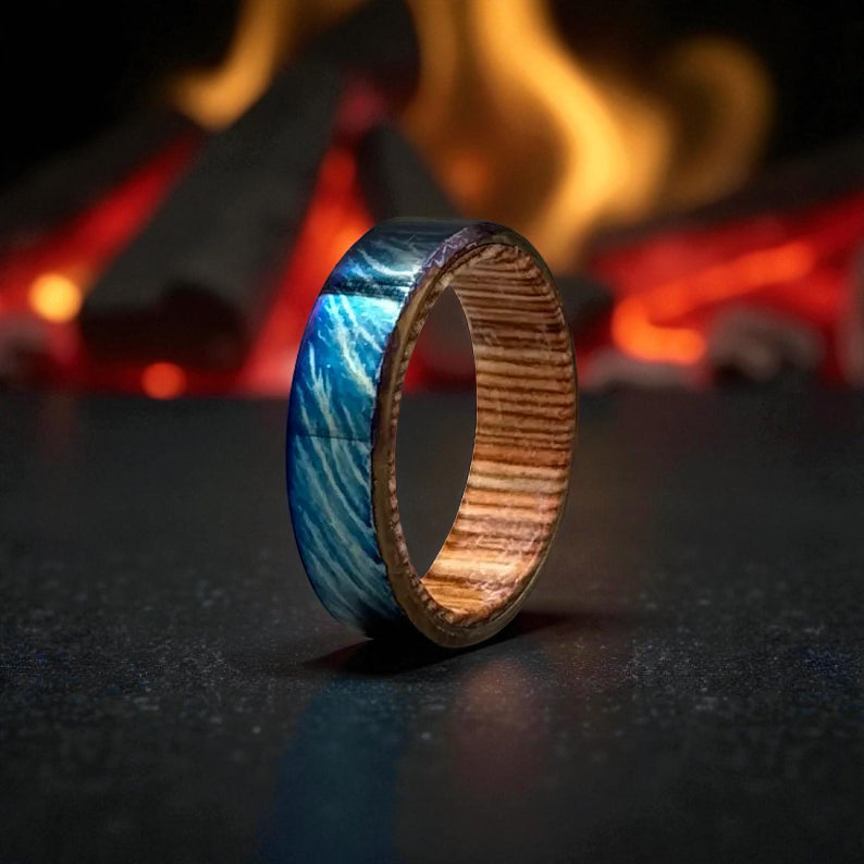 Close-up of blue titanium ring with wooden inner band on dark textured surface
