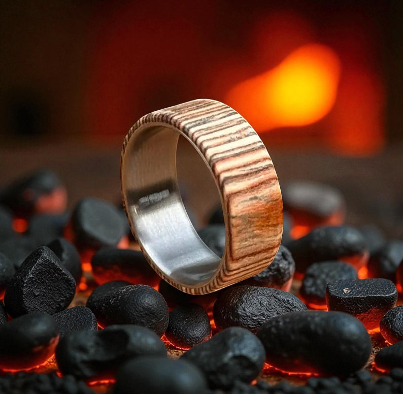 Titanium ring with wood grain inlay, glowing with firelight reflection